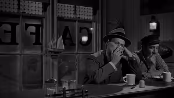 Two men in hats sit smoking at a diner counter