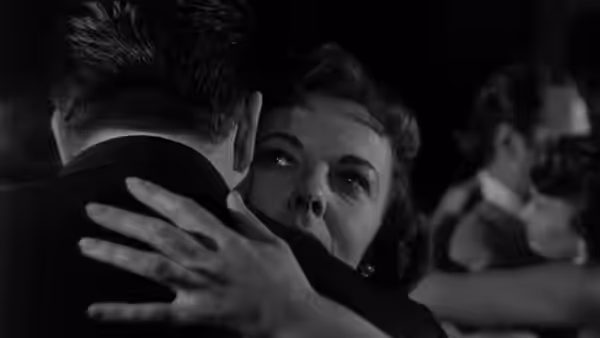 A woman embraces a man, her hand resting across his shoulder