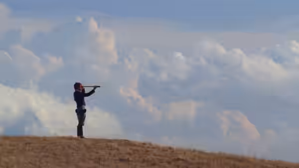 a man standing on a hill looking through a spyglass