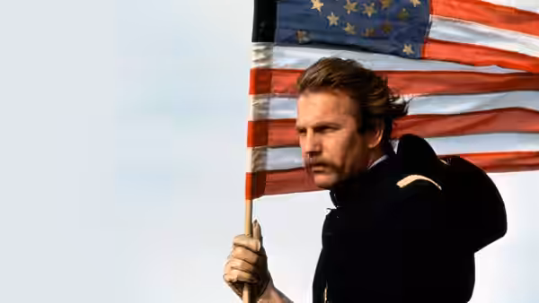 Lieutenant Dunbar (Kevin Costner) holding the American flag outdoors