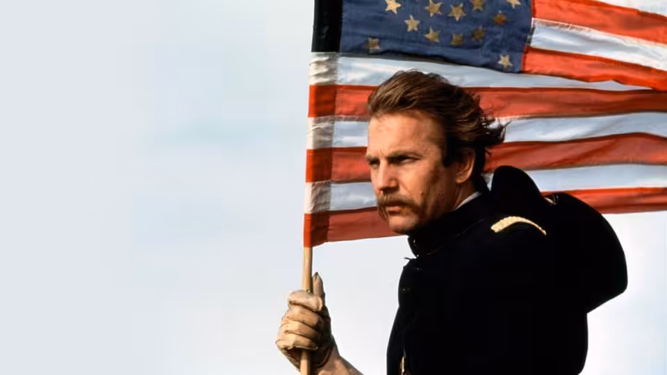 Lieutenant Dunbar (Kevin Costner) holding the American flag outdoors