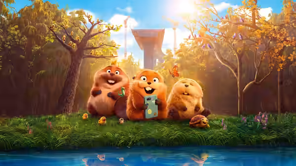 Three furry animals sit on grass by a river while one holds a device