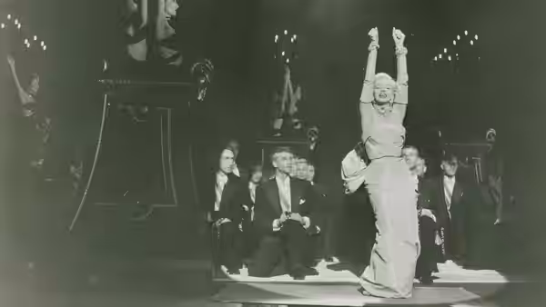 Lorelei Lee (Marilyn Monroe) hangs upside down above seated men on a stage
