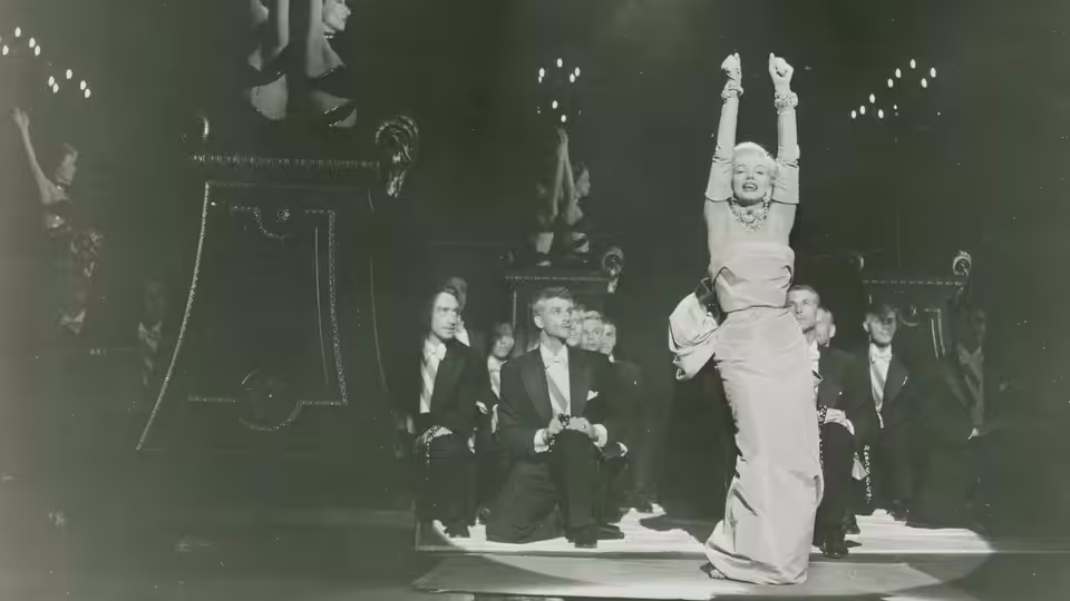 Lorelei Lee (Marilyn Monroe) hangs upside down above seated men on a stage