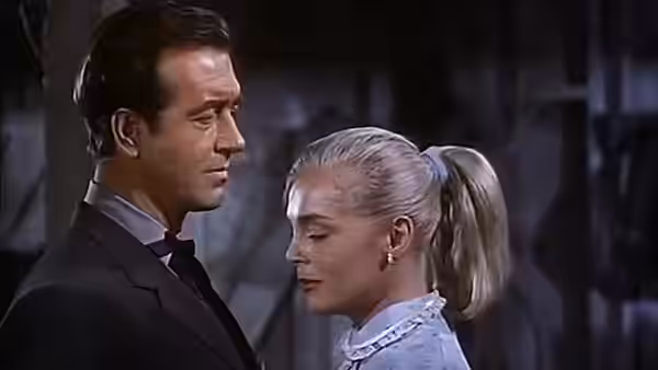 A man in a tuxedo stands beside a woman in a pale blue dress