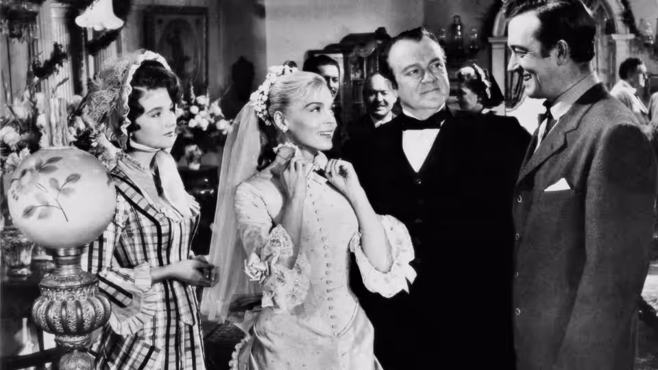 Dan Ballard (John Payne) stands beside his bride as wedding guests gather around them