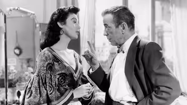 Maria Vargas (Ava Gardner) speaks with Harry Dawes (Humphrey Bogart) indoors
