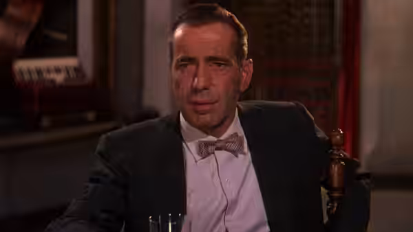 Harry Dawes (Humphrey Bogart) sits alone in a chair indoors