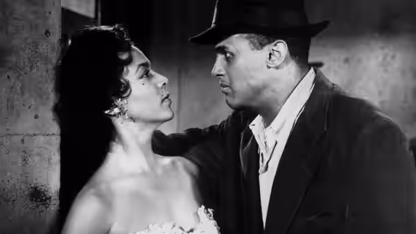 A woman in a strapless dress faces a man in a hat