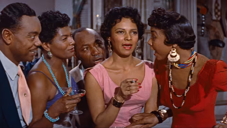 A woman in a red dress holds a drink among guests at a party