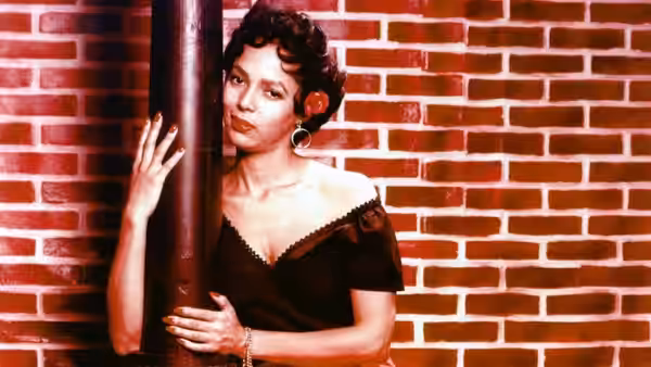 Carmen (Dorothy Dandridge) leans against a pole before a brick wall