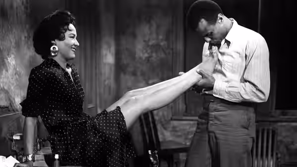 Carmen (Dorothy Dandridge) playfully raises her leg as Joe (Harry Belafonte) holds her foot
