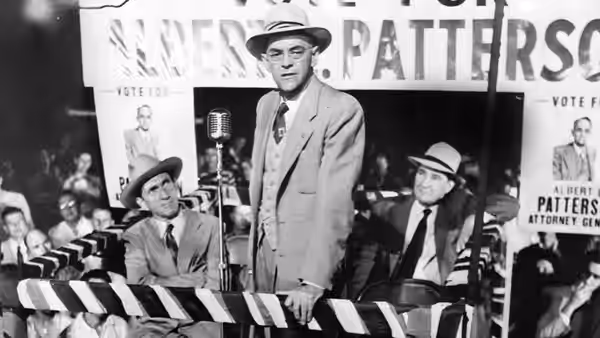 Pat Patterson (John McIntire) speaks at a campaign rally behind a striped barrier