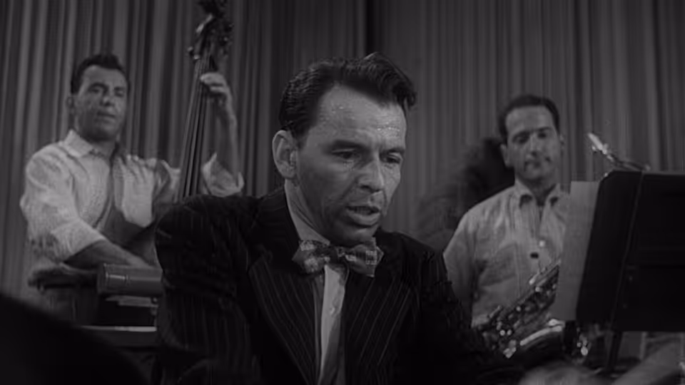 Frankie Machine (Frank Sinatra) plays drums with musicians behind him