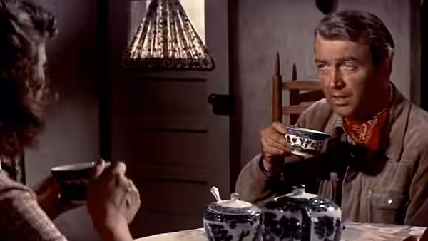 Will Lockhart (James Stewart) drinks tea across the table from a woman
