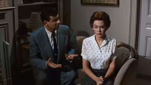 Ed Avery (James Mason) gestures beside Lou (Barbara Rush), who sits with her hands clasped