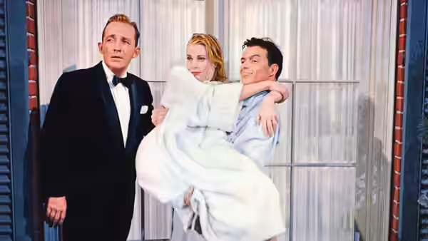 C. K. Dexter-Haven (Bing Crosby) watches as Mike Connor (Frank Sinatra) carries Tracy Lord (Grace Kelly)
