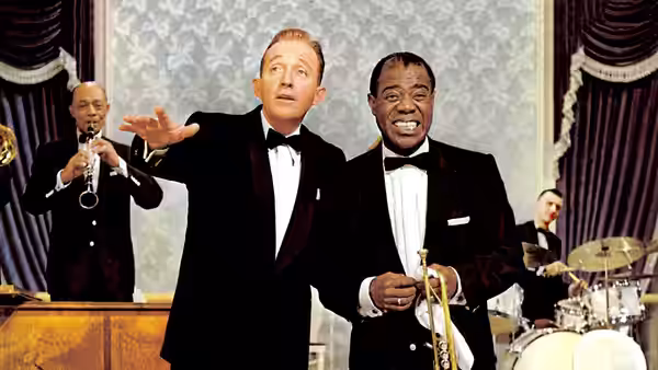 C. K. Dexter-Haven (Bing Crosby) gestures beside Louis Armstrong as the band plays