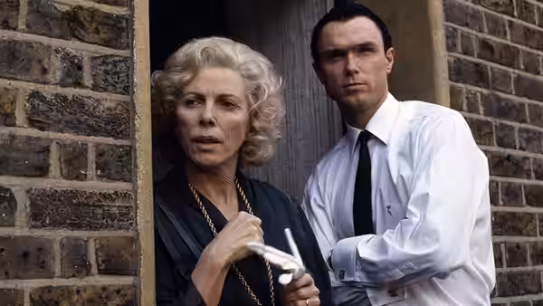 Violet Kray (Billie Whitelaw) holding spectacles beside Ronald Kray in a doorway