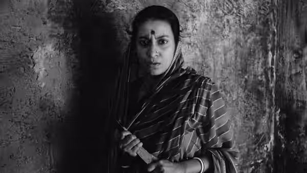 Sarbajaya Roy (Karuna Banerjee) stands in a shadowed doorway, clutching her sari