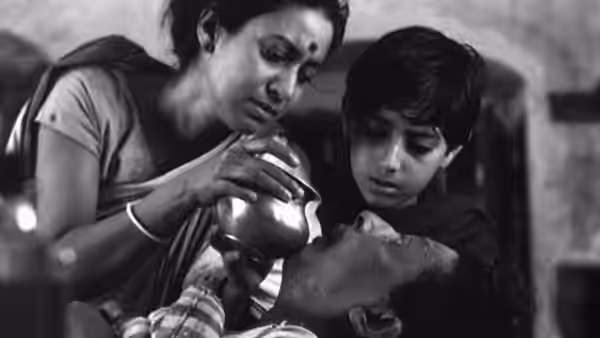 Sarbajaya Roy (Karuna Banerjee) and young Apu watch Harihar Roy drink from a cup