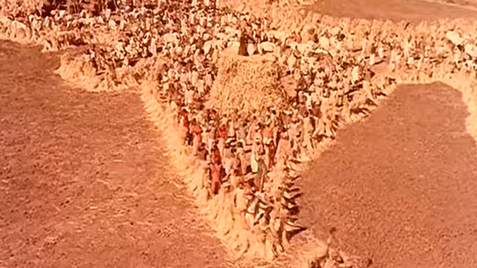 Villagers walk along a narrow path between broad fields