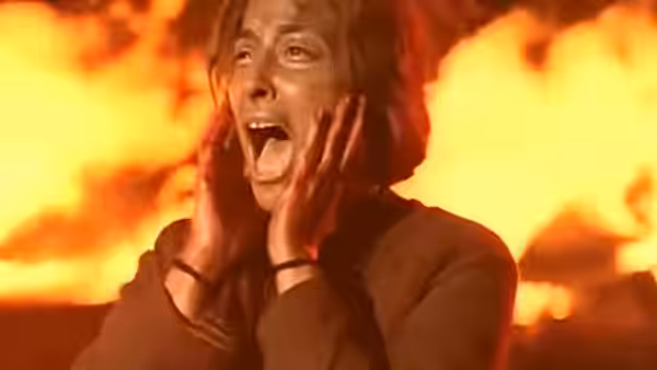 A woman cries out with flames blazing behind her