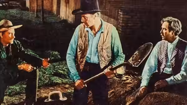 Link Jones (Gary Cooper) stands between two men beside a wooden structure