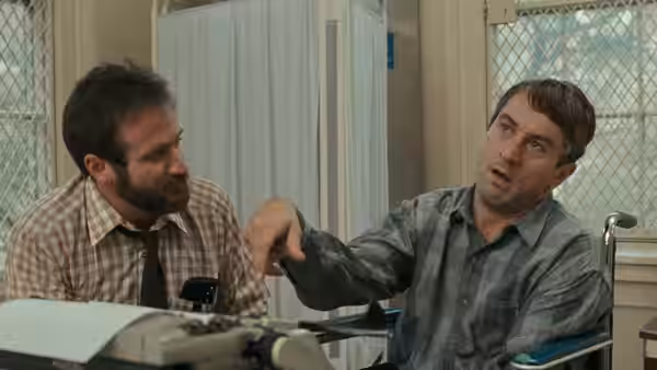 Malcolm Sayer (Robin Williams) pointing while seated with Leonard Lowe (Robert De Niro)