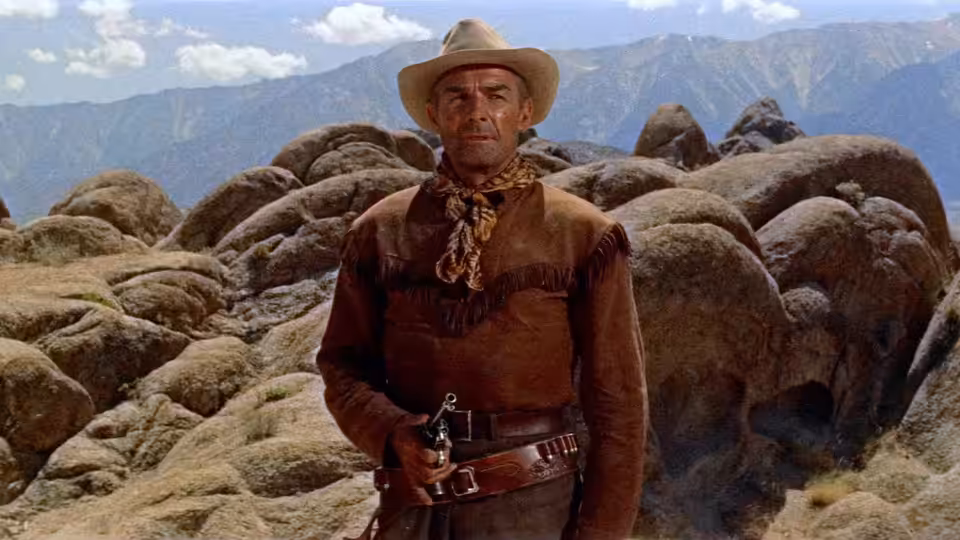 Ben Brigade (Randolph Scott) stands among boulders in the desert