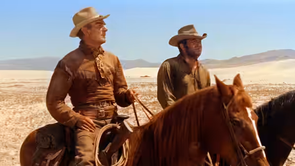 Two cowboys ride side by side across an open desert plain