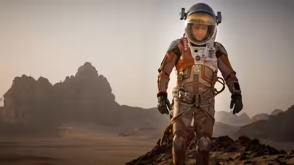 Mark Watney (Matt Damon) stands in a spacesuit on a hill in the desert