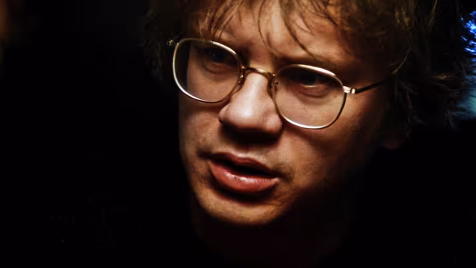 Jacob (Tim Robbins) with glasses looking upward in dim light
