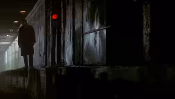 Man in a long coat standing in a dark corridor