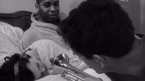 A man sits beside a woman as another person leans over them with a hair dryer