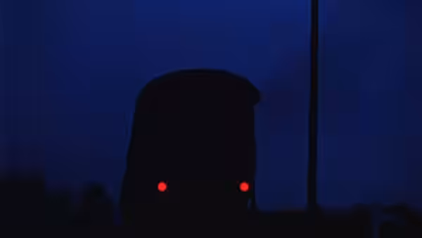 A train approaches at night with two headlights glowing