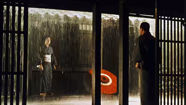 A woman in a patterned kimono faces a man across a doorway