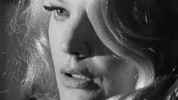 A woman looks downward, her face partly hidden by her hair