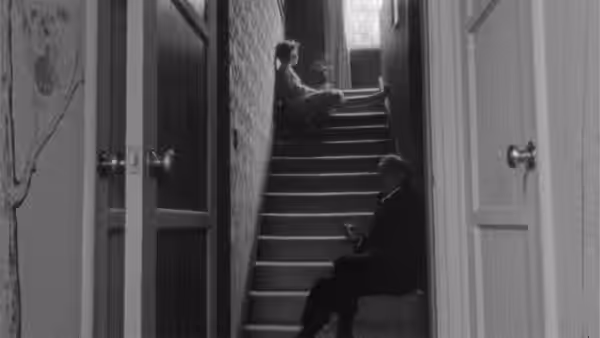 A figure sits on a staircase between open doors