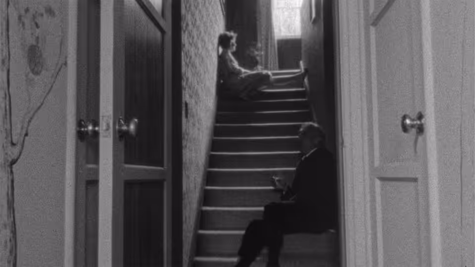 A figure sits on a staircase between open doors