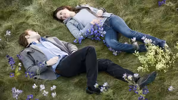 Edward Cullen (Robert Pattinson) and Bella Swan (Kristen Stewart) lie among flowers in a grassy meadow