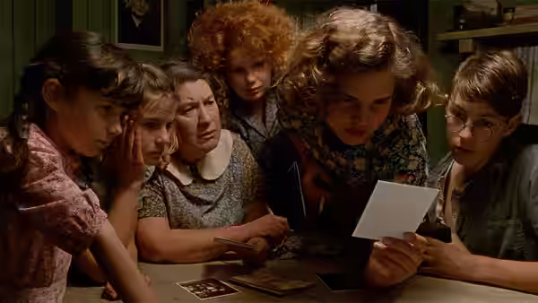 A family gathered around a table looking at old photographs