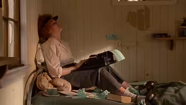 Janet Frame (Kerry Fox) reclining on a bed with a typewriter
