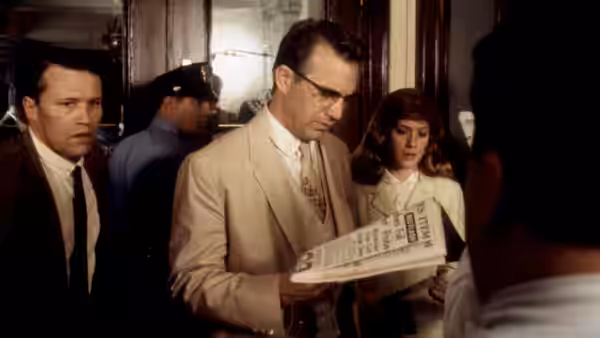 Jim Garrison (Kevin Costner) reading a newspaper among colleagues