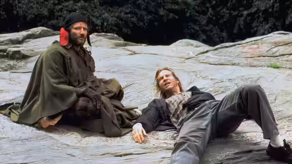 Parry (Robin Williams) sits beside Jack (Jeff Bridges) on rocky ground