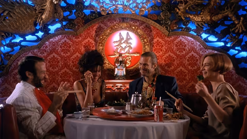 Four people eat with chopsticks at a round table in a Chinese restaurant