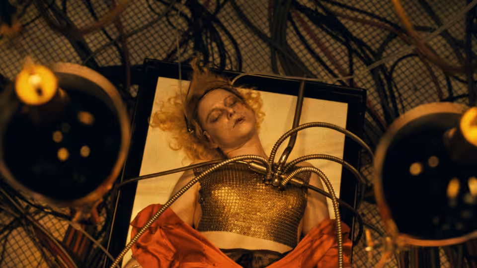Woman with curly blonde hair lies on a table connected to wires and tubes