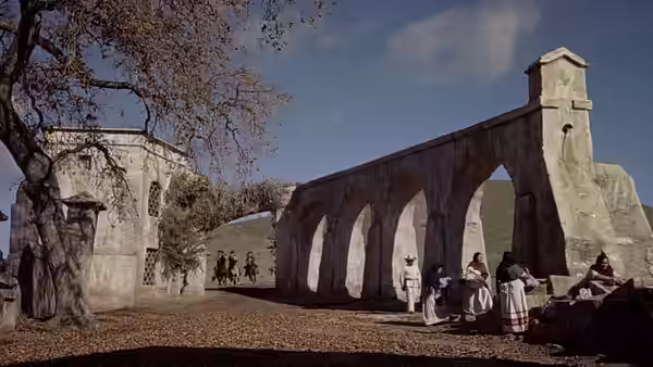 People gather beneath the arches of a mission courtyard