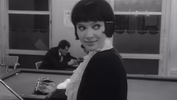Nana Kleinfrankenheim (Anna Karina) glances back as a man works behind her