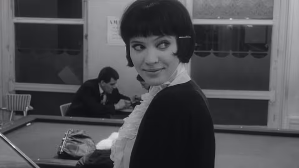 Nana Kleinfrankenheim (Anna Karina) glances back as a man works behind her